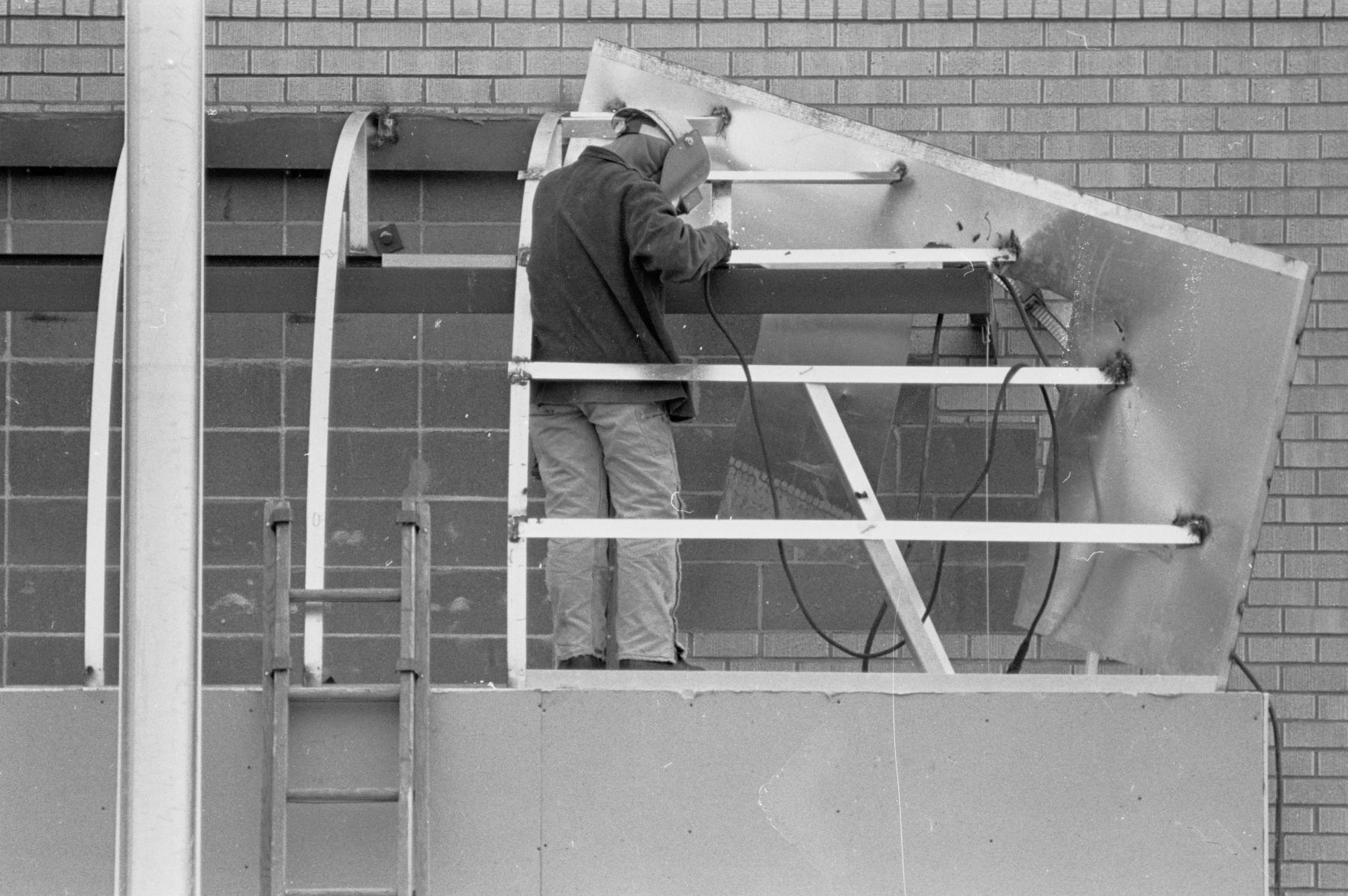 Welder working on West Park Plaza awning, 1985